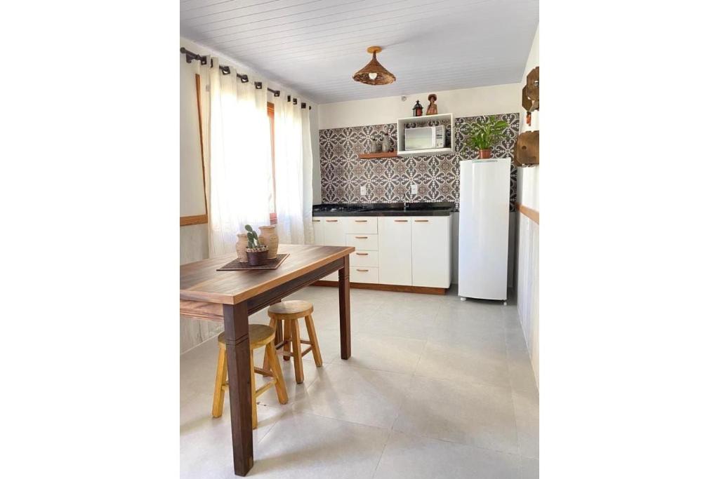 a kitchen with a wooden table and a refrigerator at Pousada Mapuche in São José