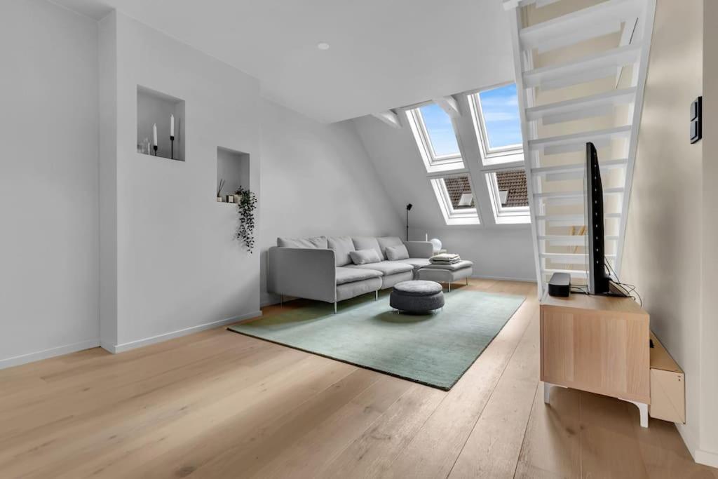 a white living room with a couch and a stair at Luxurious Penthouse in the Middle of City Center in Bergen