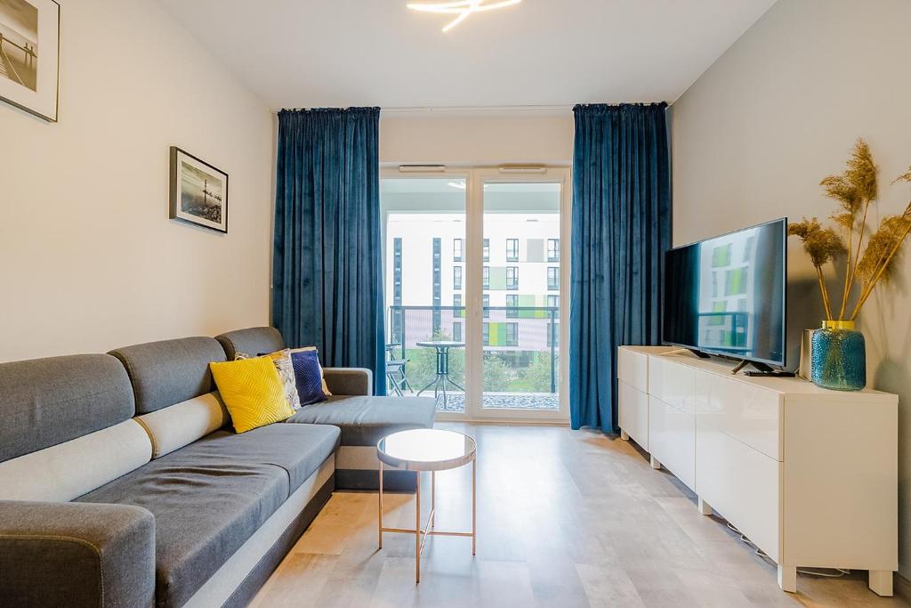 ein Wohnzimmer mit einem Sofa und einem TV in der Unterkunft Family Apartment Żoliborz by Renters in Warschau