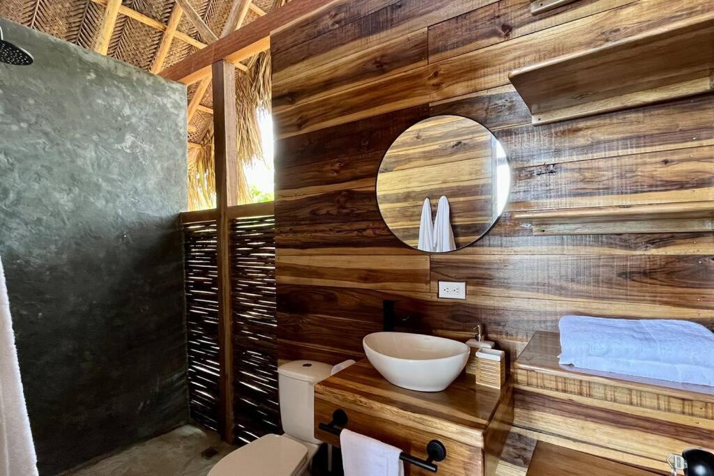 uma casa de banho com uma parede de madeira, um lavatório e um espelho. em Cielva Tayrona Cabaña Amanecer em Los Naranjos