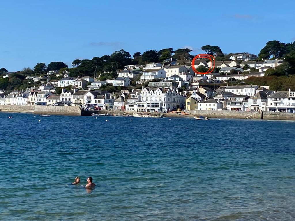 two people swimming in the water in front of a beach at Fresh, bright house, fab views, 6 mins to the sea, onsite parking x 2 in Saint Mawes