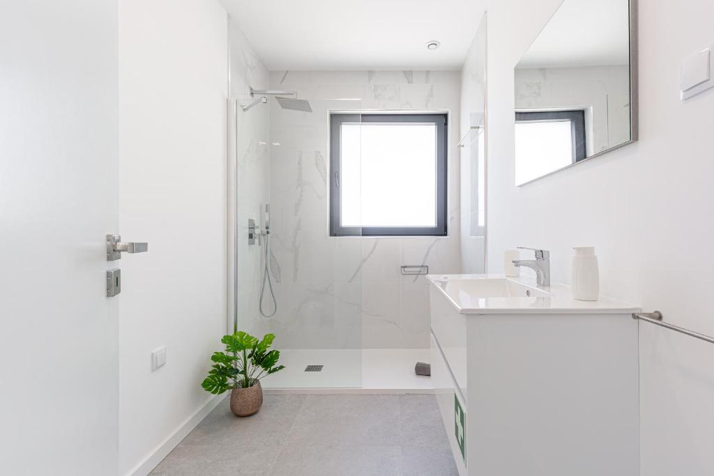 a white bathroom with a sink and a shower at Villa Locki in Lourinhã