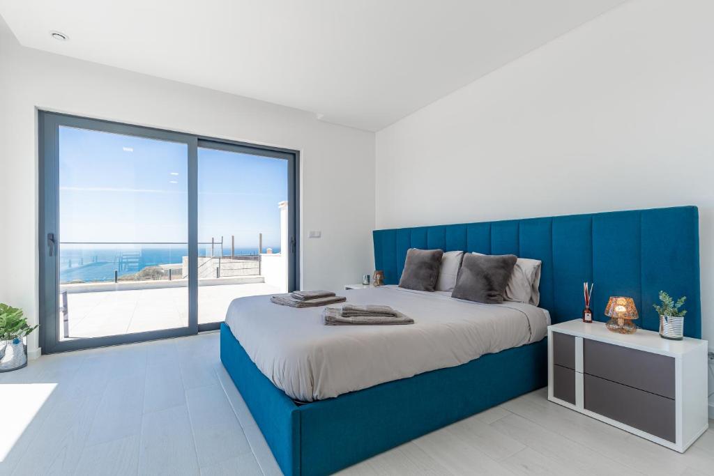 a bedroom with a blue bed and a large window at Villa Locki in Lourinhã