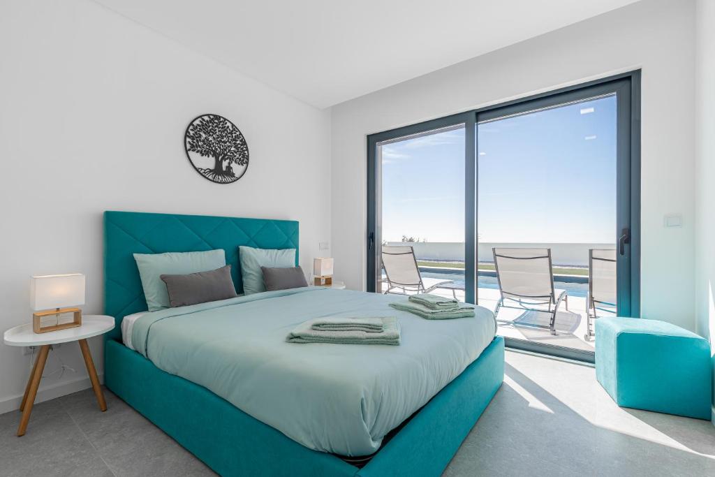 a bedroom with a large bed with a view of the ocean at Villa Locki in Lourinhã