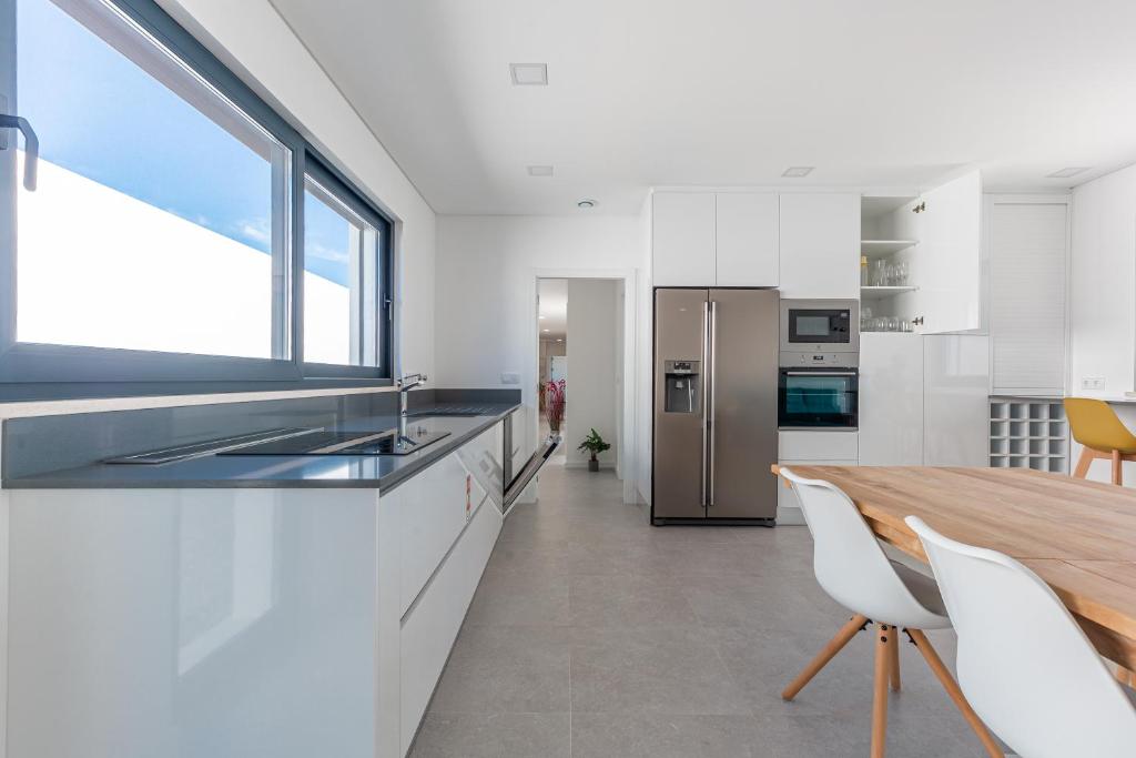 a kitchen with white cabinets and a wooden table at Villa Locki in Lourinhã