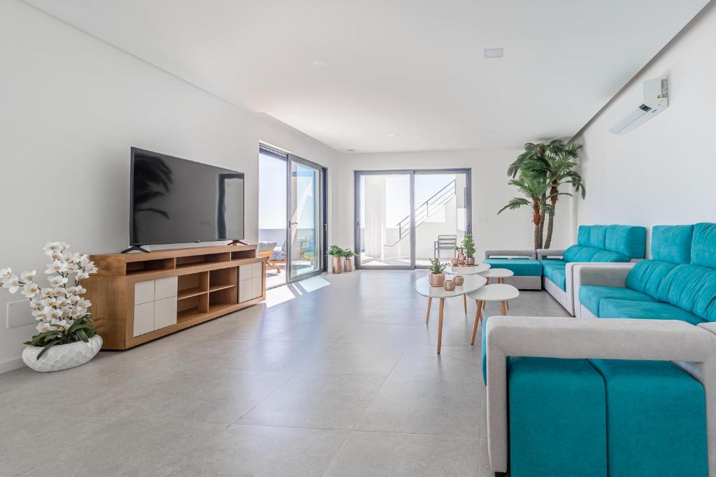 a living room with a blue couch and a tv at Villa Locki in Lourinhã
