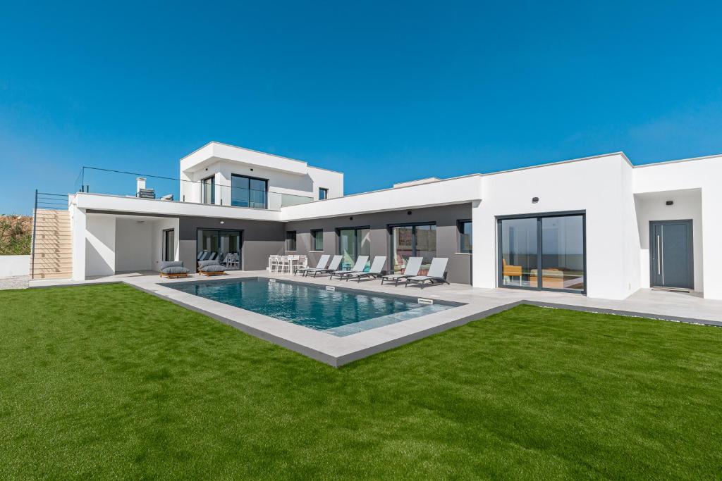 a villa with a swimming pool and green grass at Villa Locki in Lourinhã