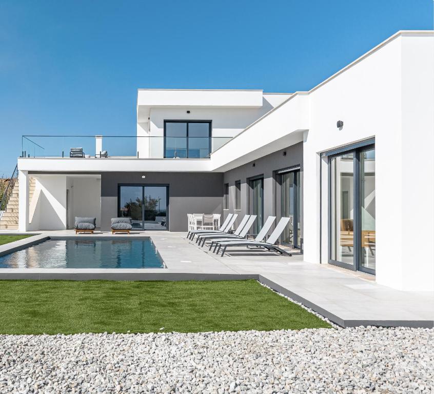 a modern house with a swimming pool and lawn at Villa Locki in Lourinhã