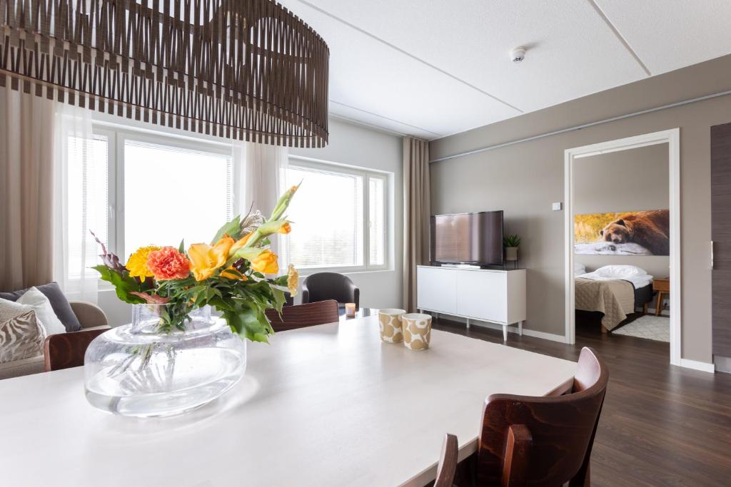 Vuokatti Booking Suites في فوكاتي: غرفة معيشة مع طاولة مع إناء من الزهور