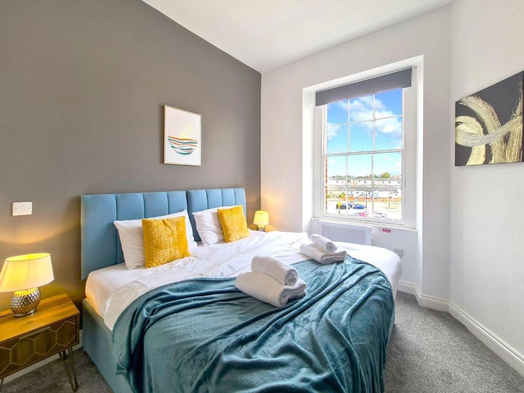een slaapkamer met een bed met gele kussens en een raam bij Margaret's Quattro in Cheltenham