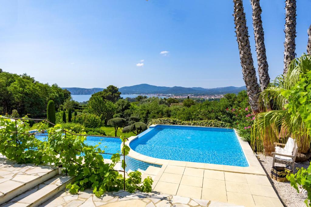 ein Swimmingpool in einem Garten mit Palmen in der Unterkunft Golfvilla Riviera in Grimaud