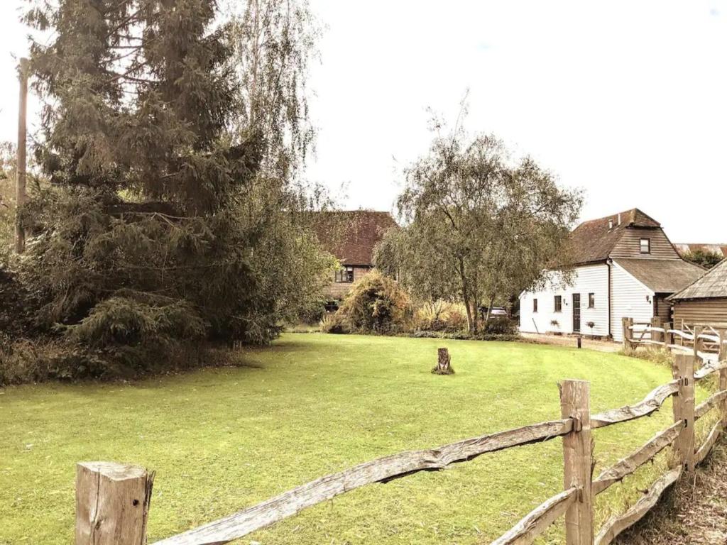 a fence in front of a yard with a house at Pass the Keys The Granary the perfect Country Cottage all year in Ashford