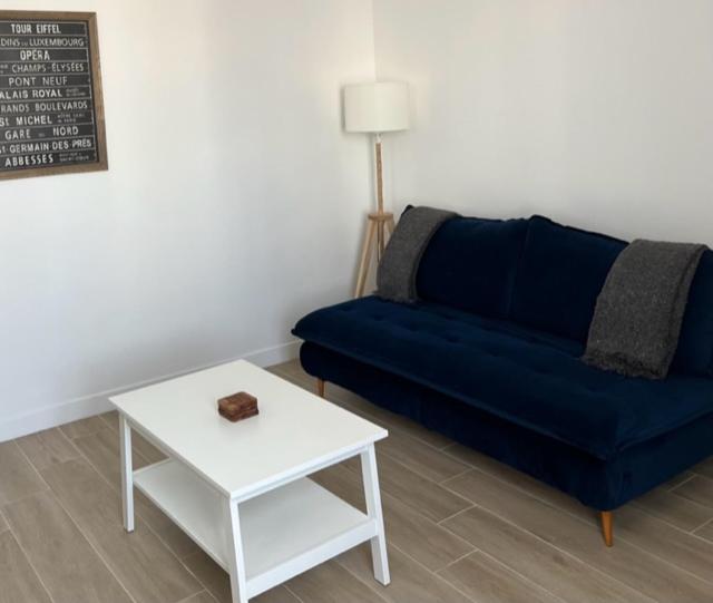 ein Wohnzimmer mit einem blauen Sofa und einem Tisch in der Unterkunft Chez Jérôme et Dina in Aubervilliers