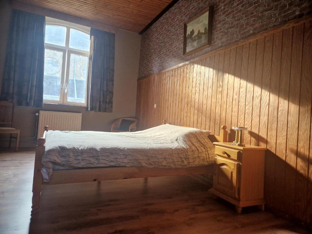 a bedroom with a bed and a wooden wall at B&B 't Kloaster in Hulsberg