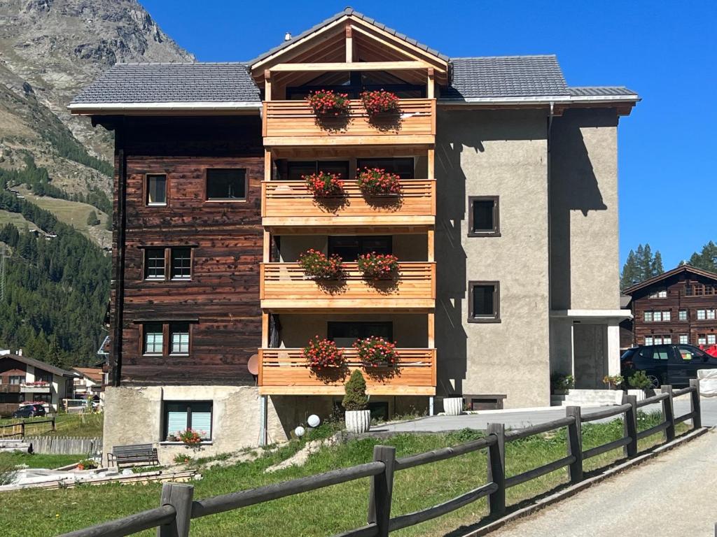 a building with potted plants on the balconies of it at Ferienhaus Capricorn **** in Saas-Grund