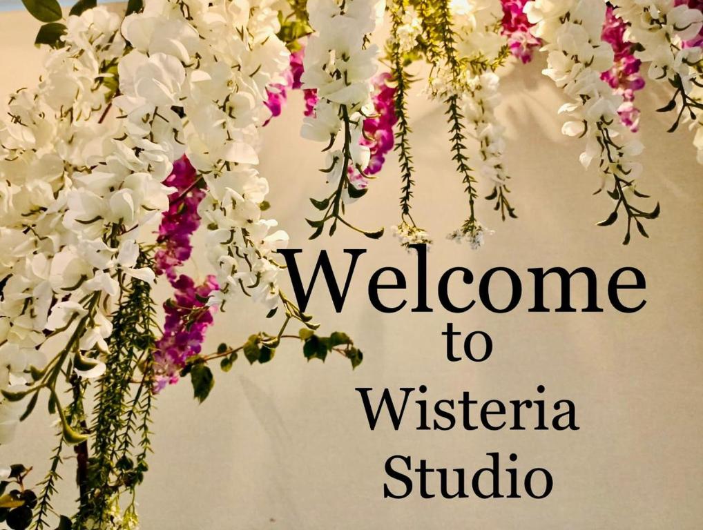 Una señal que dice bienvenido al estudio Wisteria con flores en Wisteria, en Nafpaktos