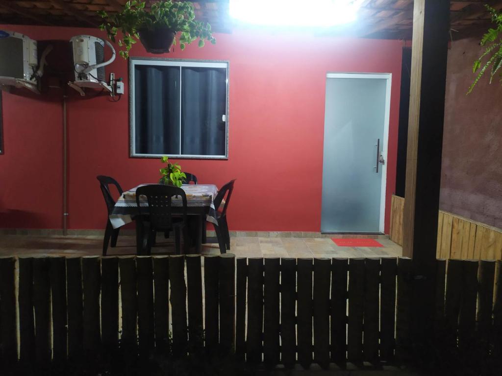 una mesa y sillas frente a una pared roja en Studio Mar & Sol en Armacao dos Buzios