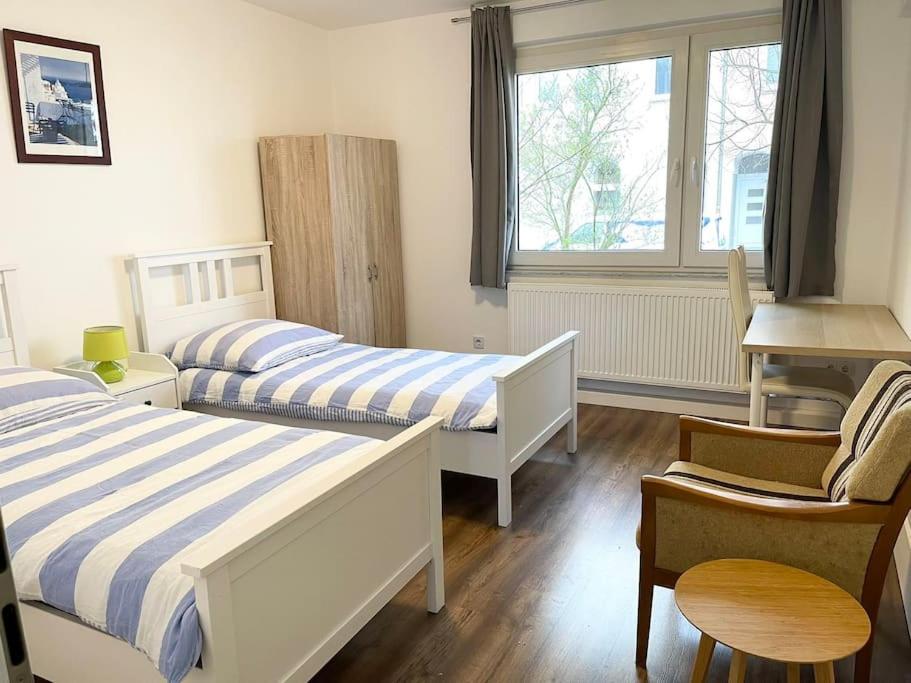 1 dormitorio con 2 camas, silla y ventana en near Düsseldorf Messe and Airport, two Bedrooms, Parking, Kitchen and Garden, en Duisburg