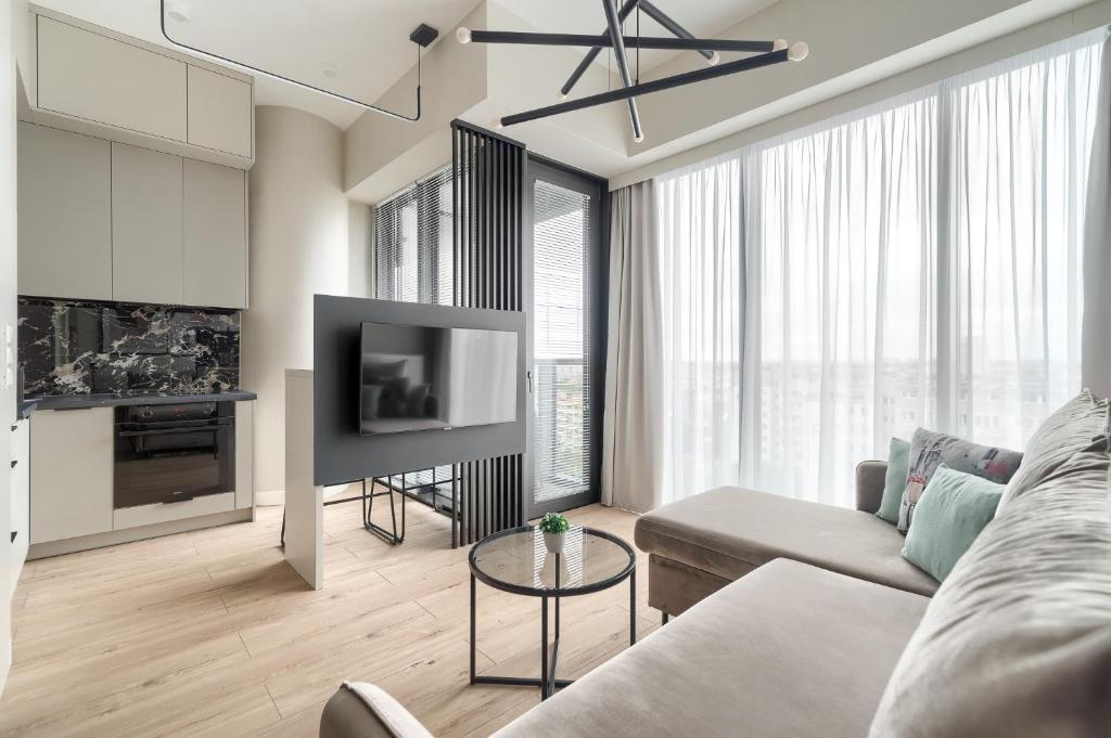 Margi Smart Apartament HANZA POOL SAUNA في شتتين: غرفة معيشة مع أريكة وتلفزيون