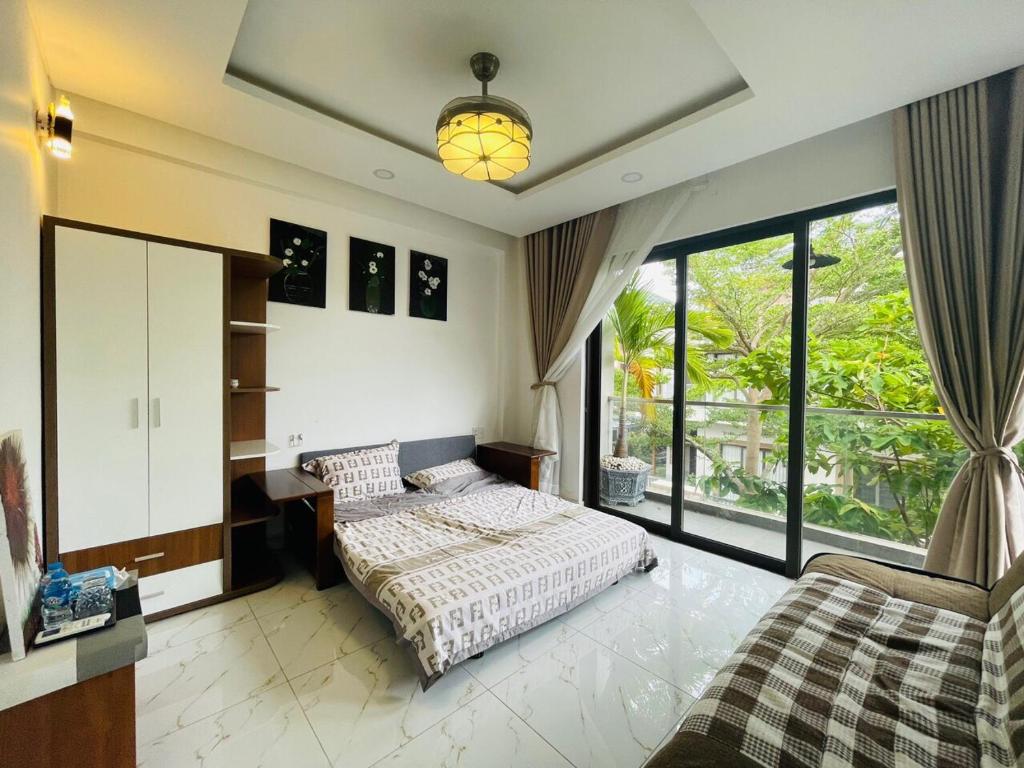 a bedroom with a bed and a desk and windows at Kim Villa Swan Bay - Zone 8 in Phước Lý
