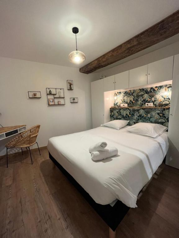 a bedroom with a large white bed with towels on it at La Cour Chartraine - Cosy appartement avec cour extérieur à Blois in Blois