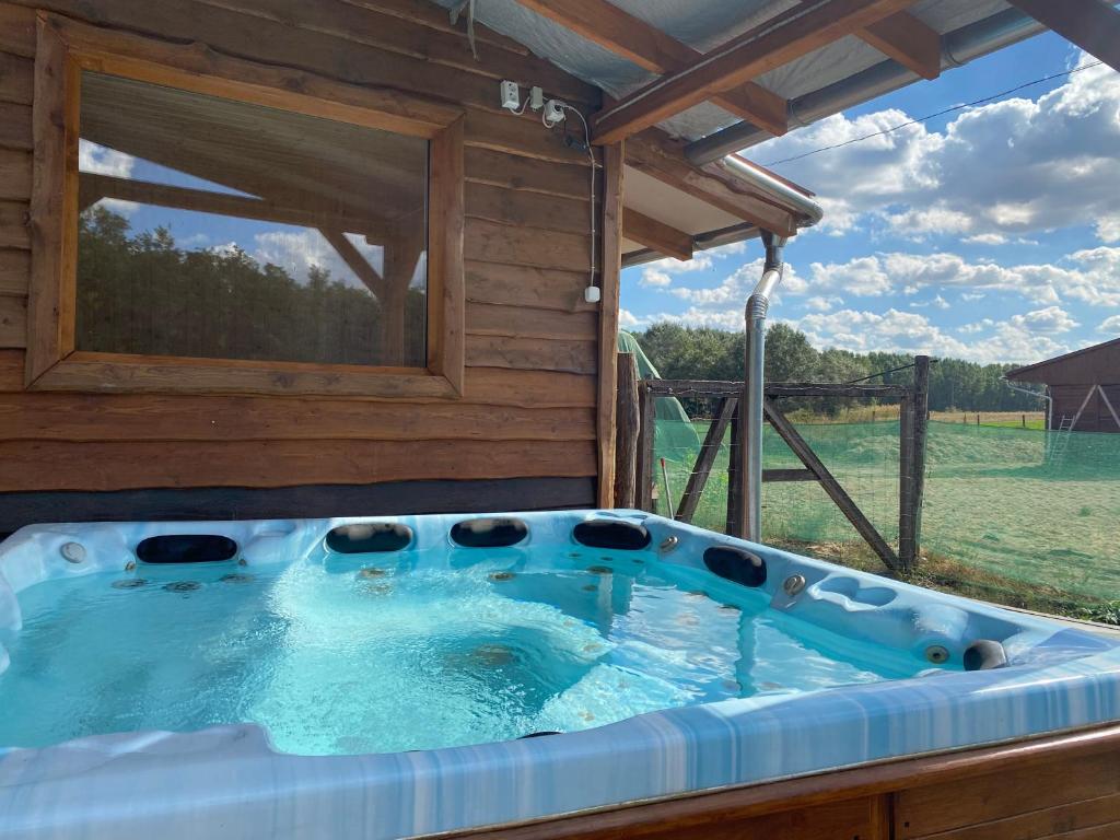 einen großen Whirlpool in einer Hütte mit Fenster in der Unterkunft Tündér Pension in Mogyoród