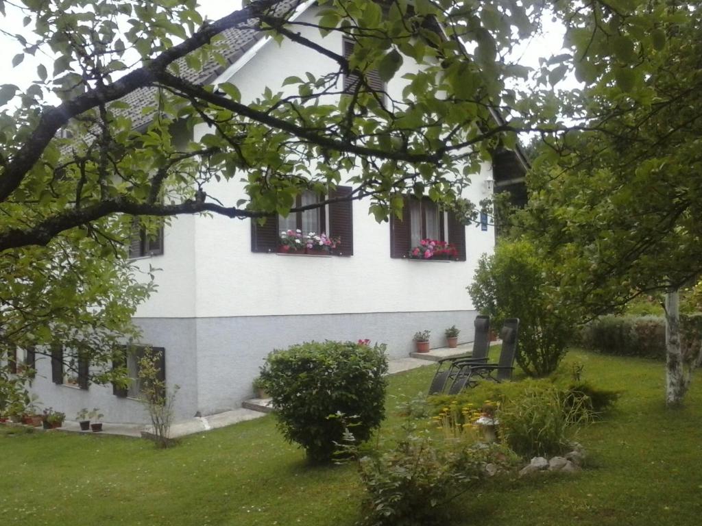 une maison blanche avec des fenêtres et des fleurs dans une cour dans l'établissement House Nina, à Poljanak