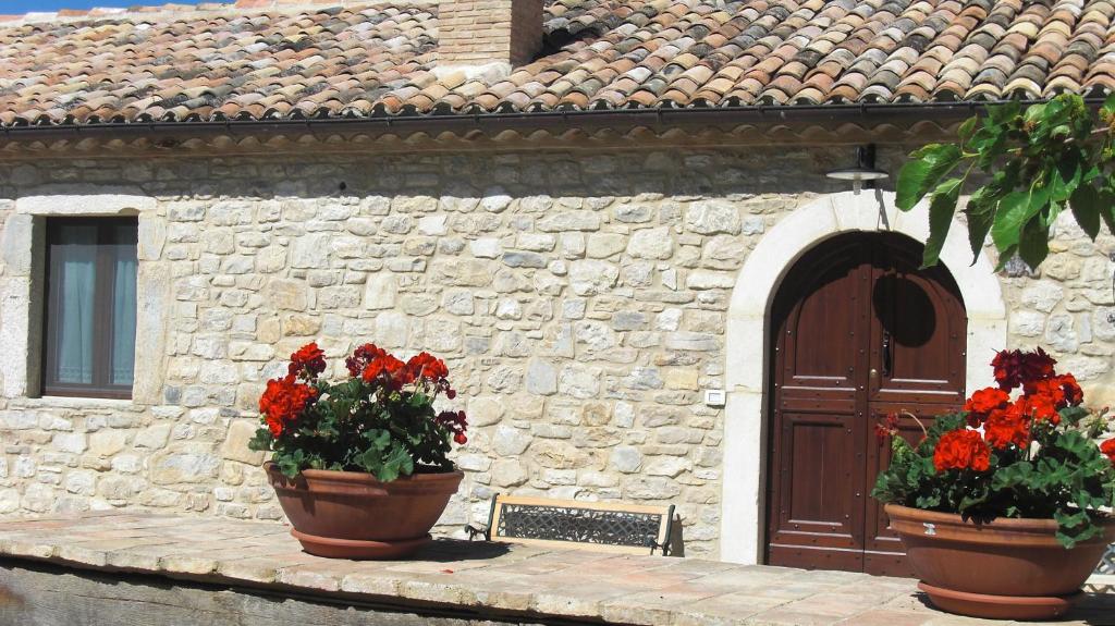 due vasi di fiori rossi di fronte a un edificio di BB Casavacanze Corneto a Bomba