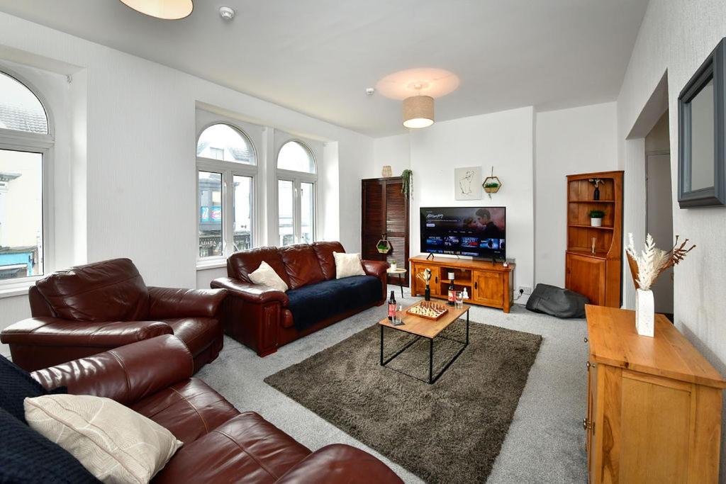 a living room with a leather couch and a tv at Spacious 2 bedroom apartment in the heart mumbles in The Mumbles