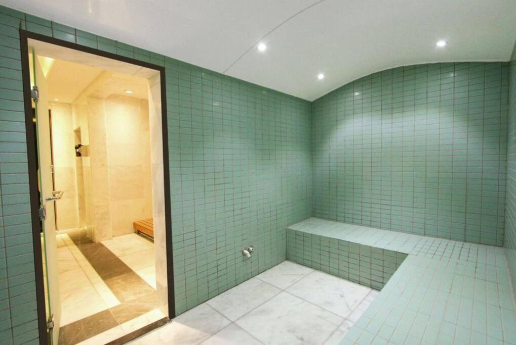 a bathroom with green tiled walls and a walk in shower at Apartment number 365 Era View in Manama