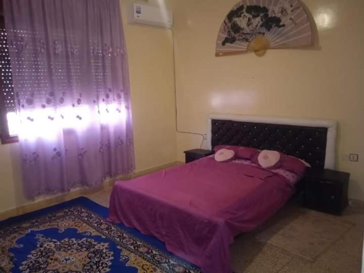 - une chambre avec un lit violet et des oreillers roses dans l'établissement Rez-de-chaussée villa touta, à Béni Mellal