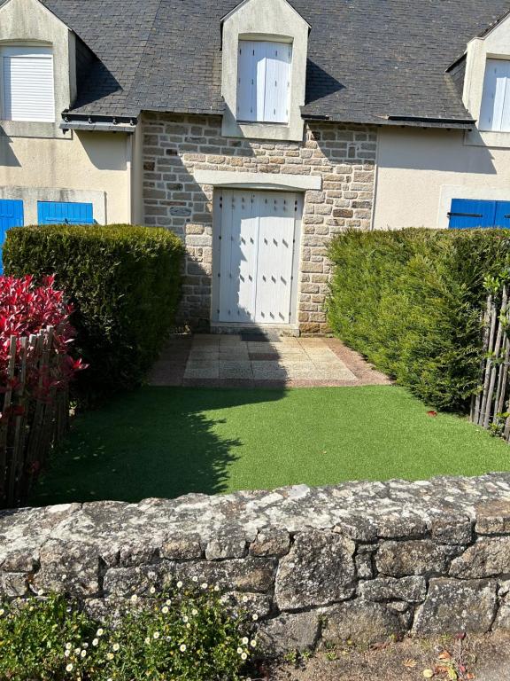 ein Haus mit einer weißen Tür und einer Steinmauer in der Unterkunft KERVILLEN in La Trinité-sur-Mer