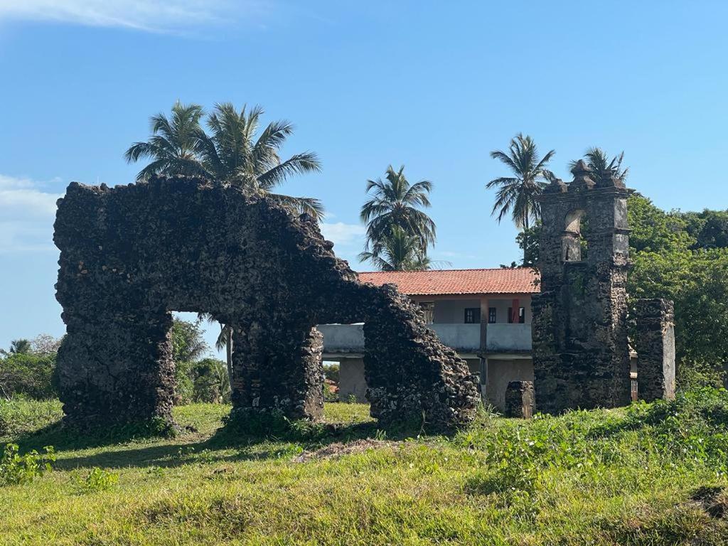 an old stone building with palm trees in the background at Pousada Reloday in Salvaterra