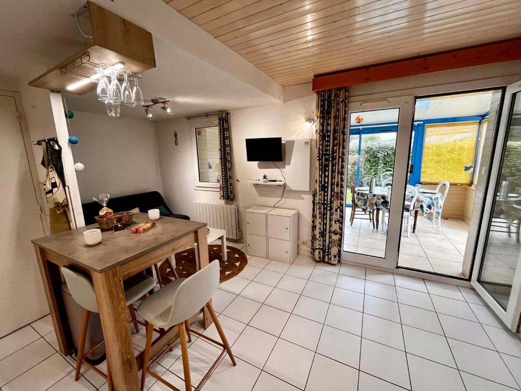 a living room with a table and chairs and a television at Keraven, charmante maisonnette, piscine commune 1-4 personnes in Moëlan-sur-Mer