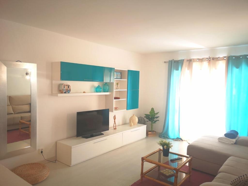 a living room with a couch and a tv at Caparica Ocean View in Costa da Caparica