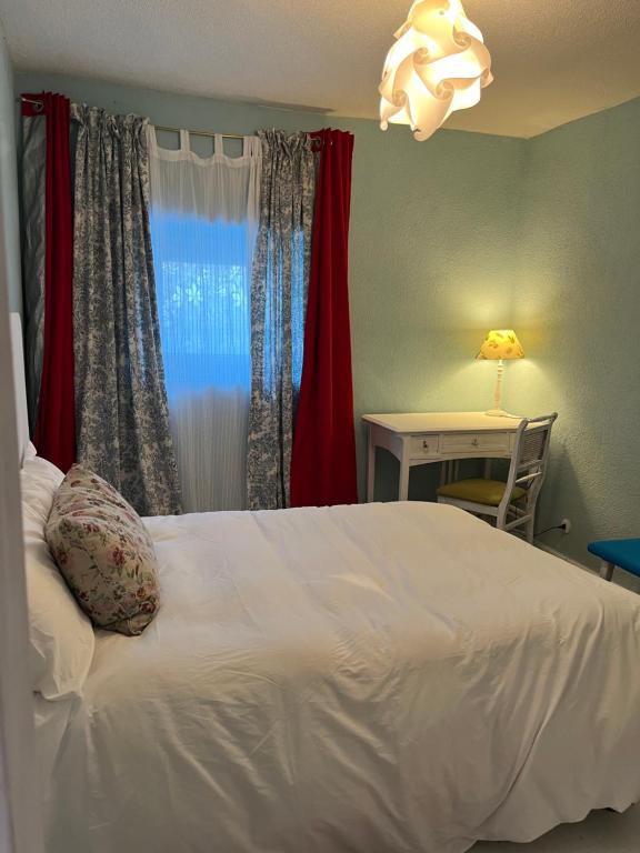 1 dormitorio con cama blanca y escritorio con lámpara en Casa Rústica, en Zarzalejo