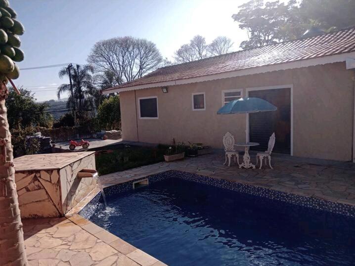 a pool with a table and an umbrella next to a house at Quarto Privativo em Santana de Parnaiba 02 in Santana de Parnaíba