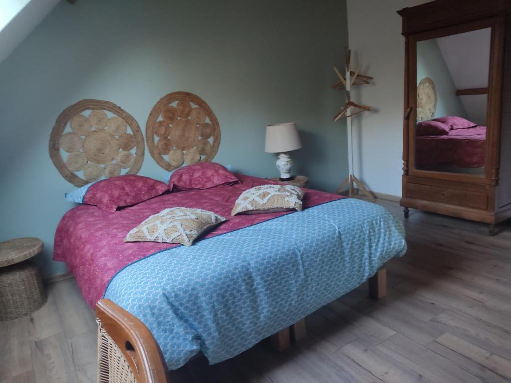 a bedroom with a bed with a blue blanket and a mirror at Au pied de la colline in Alembon