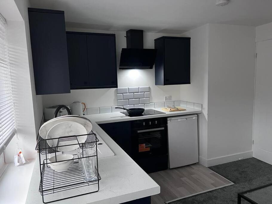 eine Küche mit schwarzen Schränken und einer weißen Arbeitsplatte in der Unterkunft Harmony home Lindley Huddersfield in Lindley