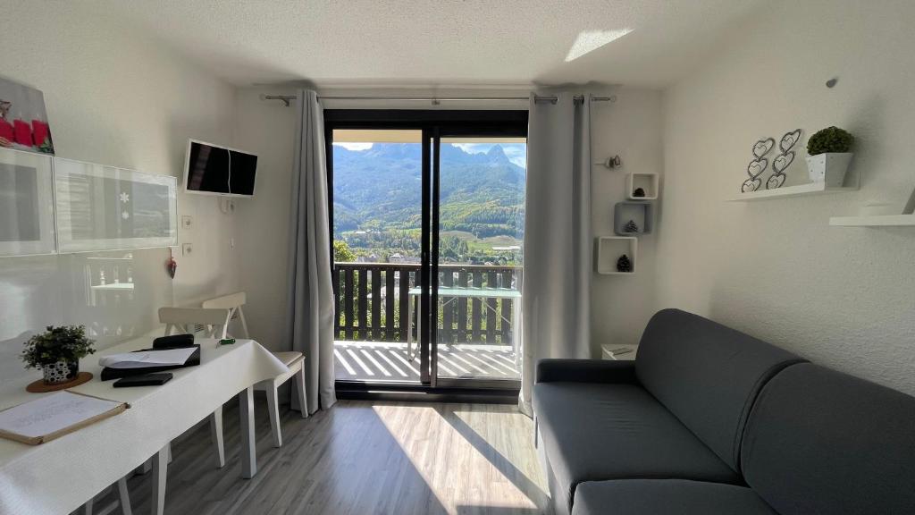 d'un salon avec un canapé et un bureau ainsi que d'un balcon. dans l'établissement La Méa, à Barcelonnette