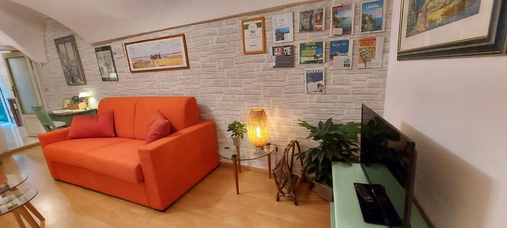 sala de estar con silla naranja y pared de ladrillo en Suite dei Doria, en Dolceacqua