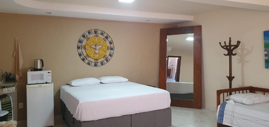 - une chambre avec un lit et une horloge murale dans l'établissement Pousada Morada dos Pássaros, à Pedro Leopoldo