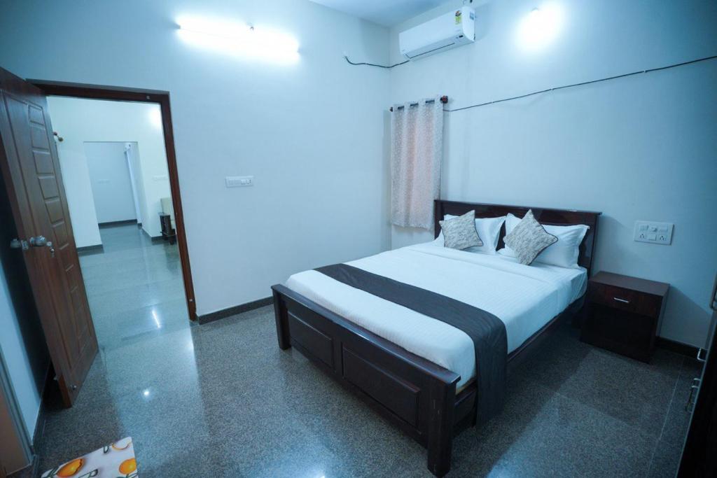 a bedroom with a bed with white sheets and pillows at Velvet Vista Premier Service Apartments in Mysore in Mysore