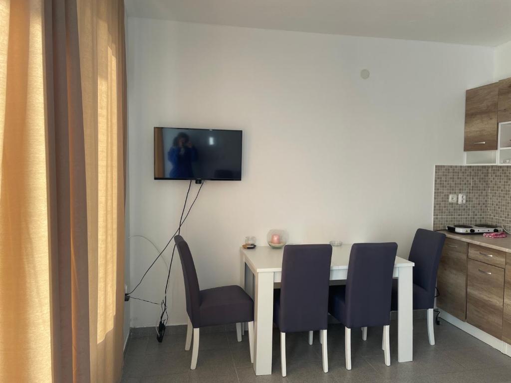 Apartmans Čuljak : طاولة طعام مع كراسي وتلفزيون على الحائط