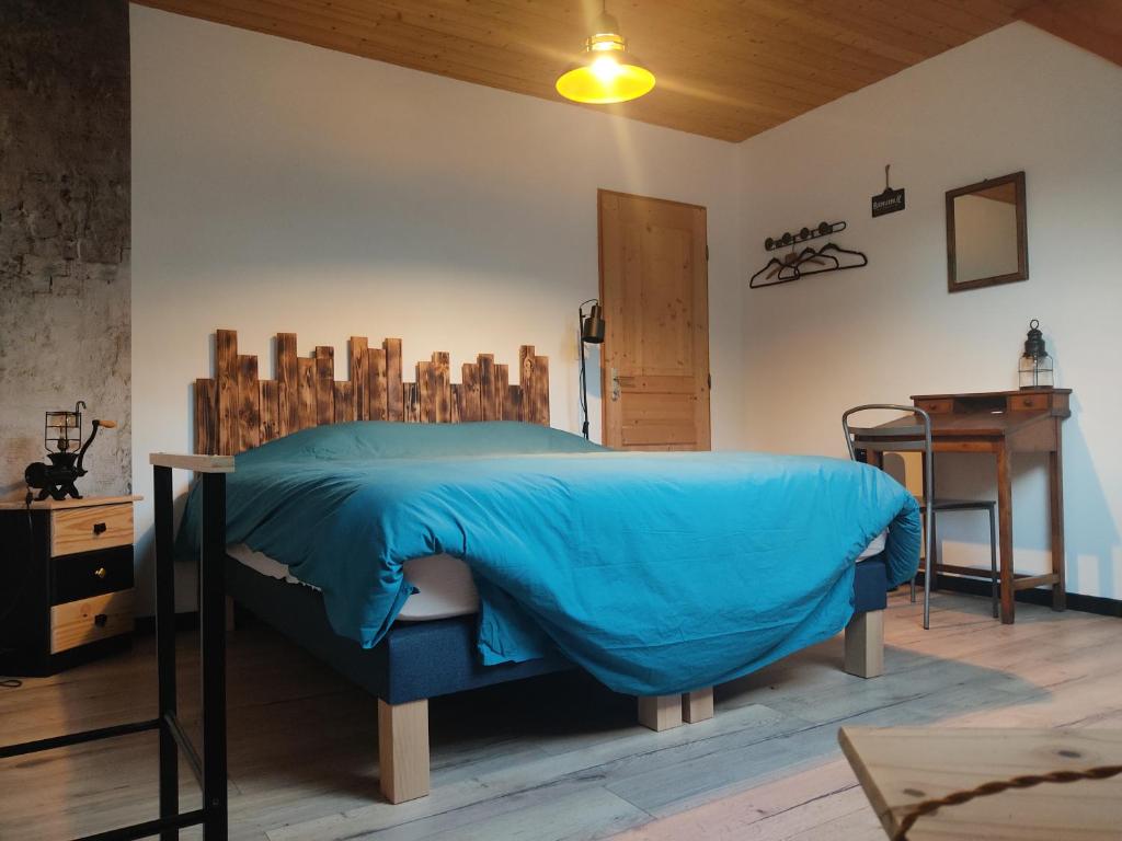 a bedroom with a bed with a blue blanket at Au pied de la colline in Alembon