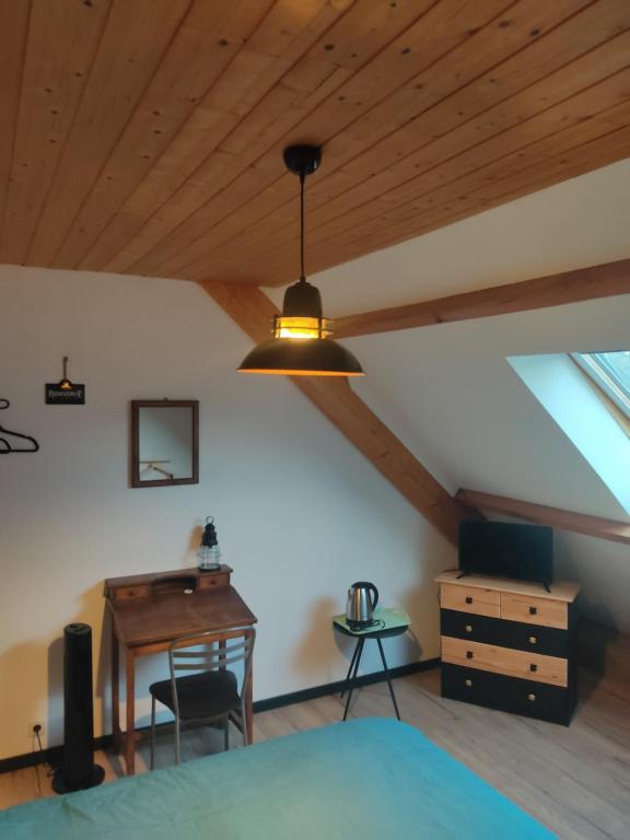 a bedroom with a wooden ceiling with a table and a desk at Au pied de la colline in Alembon