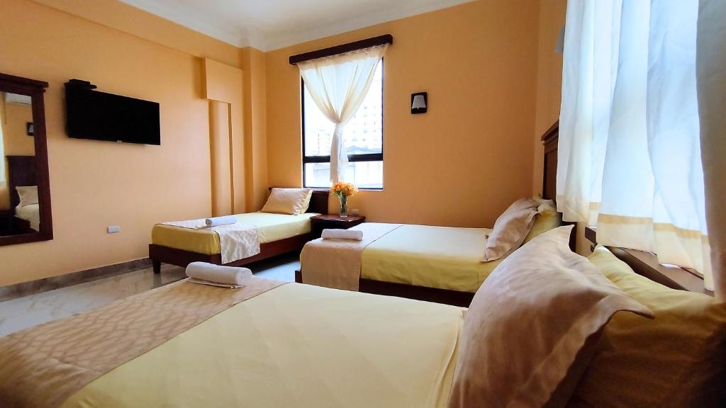 a hotel room with two beds and a television at Hostal California Inn in Guayaquil