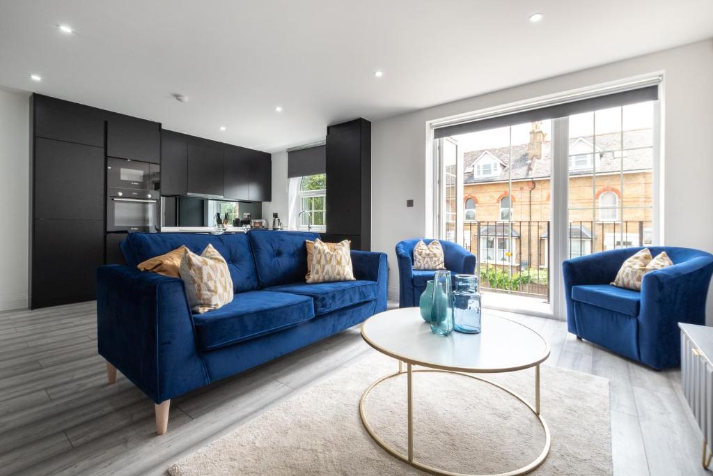 a living room with blue couches and a table at LUXURIOUS Apartments FREE parking and FREE WiFi! in Staines