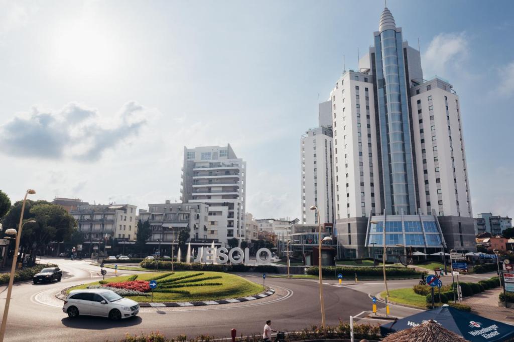 a white car driving down a road in a city at Anima Jesolo - Drago Village - Family Apartments - City Center, Pool & Garden, Beach Umbrella Included, 2 Parking Spaces in Lido di Jesolo