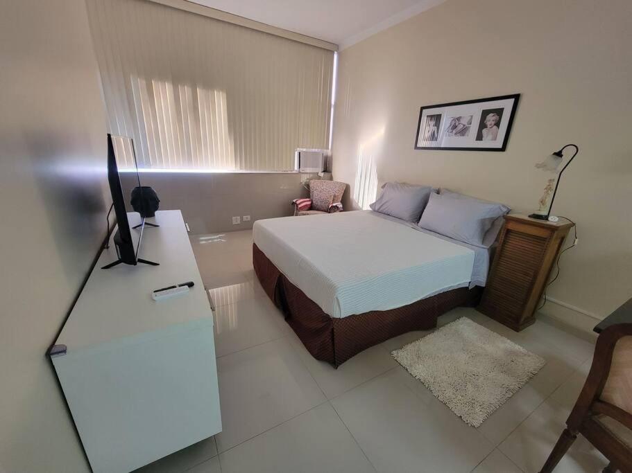 1 dormitorio con 1 cama y escritorio con TV en Espaçoso Apartamento no Centro, en Río de Janeiro